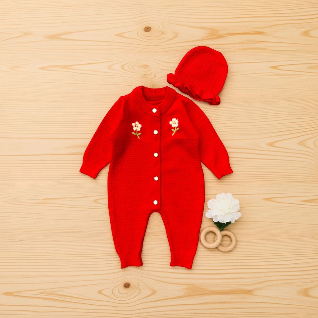 Red baby outfit with floral details on a wooden surface