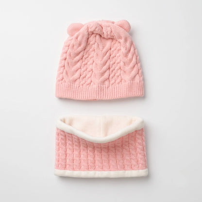 A baby knit hat and matching neck warmer set in soft pink and cream. The hat features a cable-knit pattern, ribbed brim, and two small knotted bear ears on top.