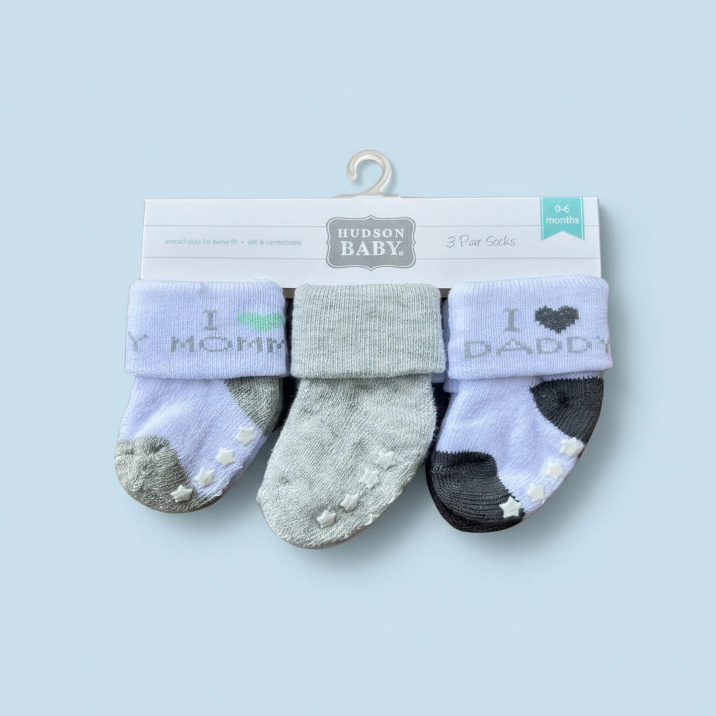 Three pairs of baby socks with 'I love Mommy' and 'I love Daddy' text on a Hudson Baby packaging.