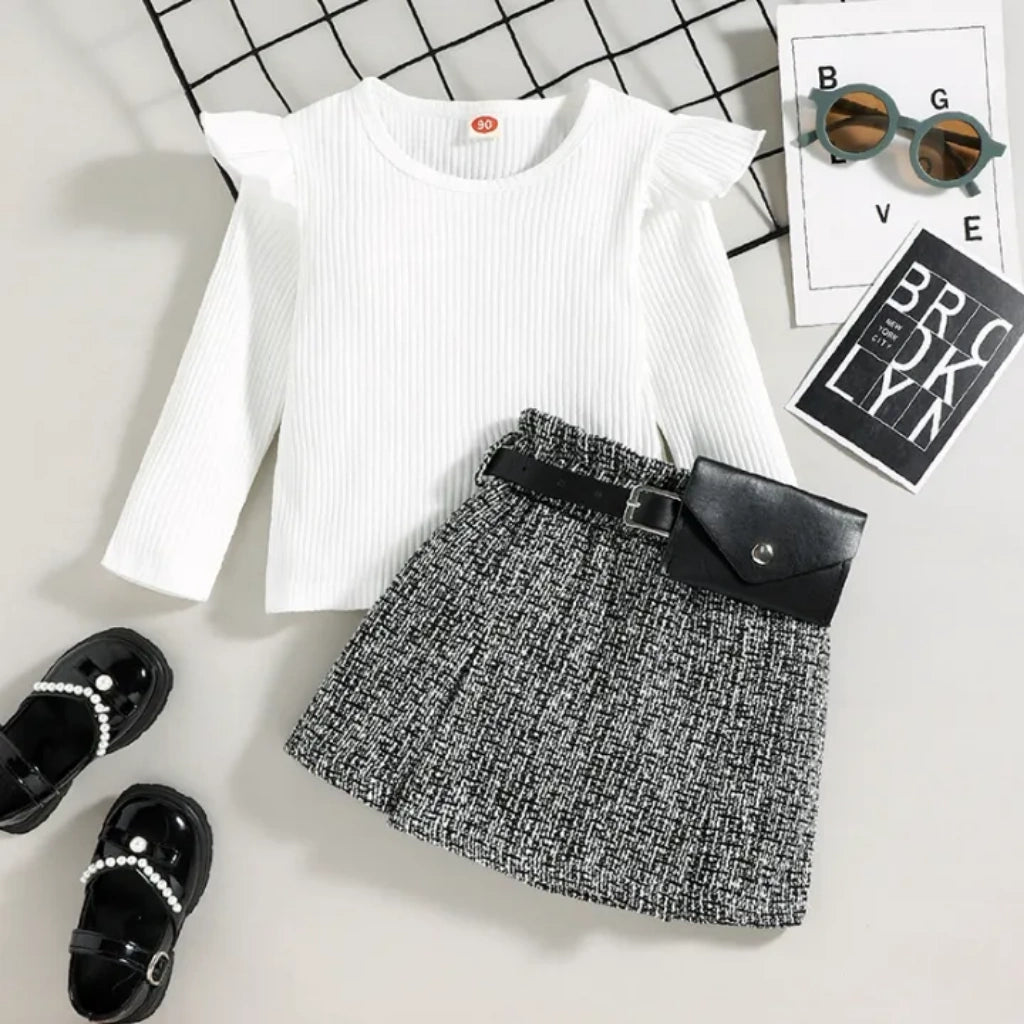 White ribbed top, black and white patterned skirt, black clutch, and black sandals on a light gray background.