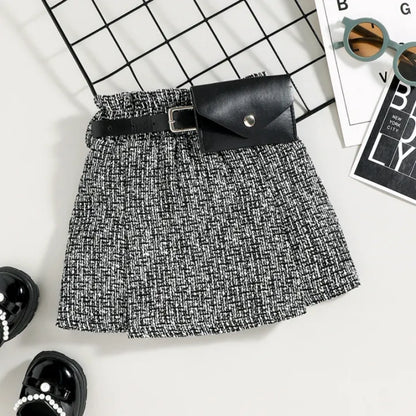 Black and white patterned skirt with a black belt and clutch on a grid background