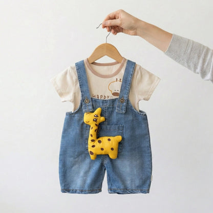 Children's denim overalls with a yellow plush toy on a hanger against a white background