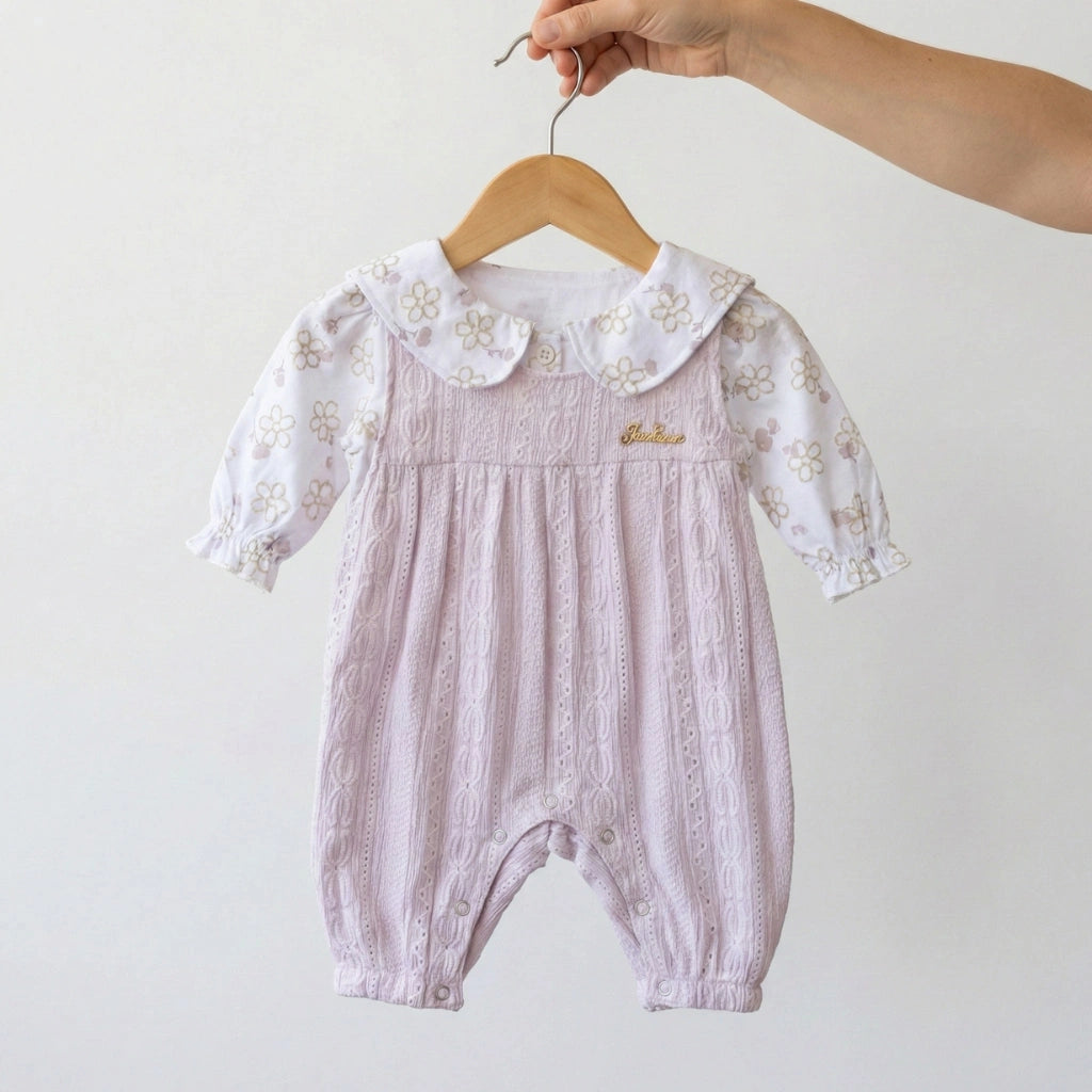 Baby romper with floral collar on a hanger against a white background