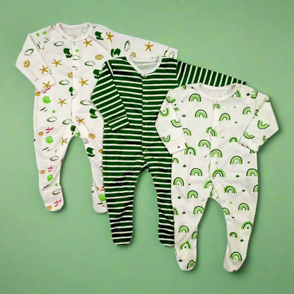 The Pack Of 3 Winter Baby Rompers – Green Lining by Alaya Junior features three cozy onesies set against a green background. The left romper showcases a white design adorned with green frogs, bears, and stars. The middle romper is green with white stripes, while the right one is white with charming green rainbows. Each romper includes snap button closures for easy changing.