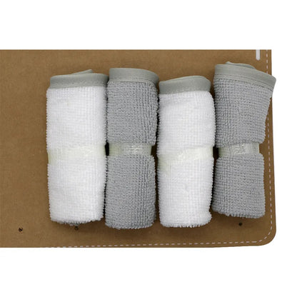 Four neatly rolled white and gray gauze bandages arranged in a row on a brown surface, secured with transparent adhesive strips, bring to mind the level of care characteristic of Alaya Junior's Elephantastic Bath Time: Set of 6 Baby Hooded Towels in Gift Packing. The white bandages are positioned on the left, while the gray ones are on the right.