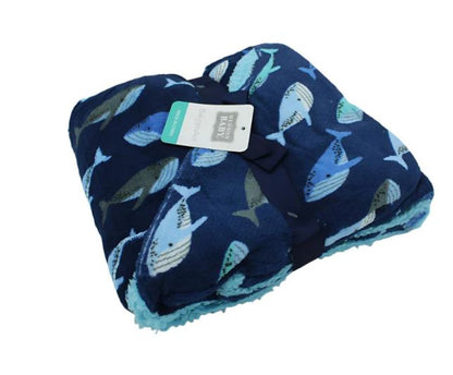 The Hudson High Quality Baby Plush Blanket, measuring 36x30 inches, in navy blue with blue and gray whales is elegantly tied with a dark blue ribbon and features an attached label.