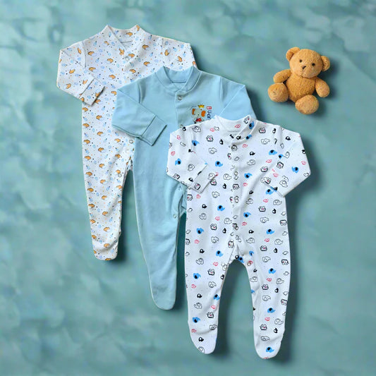 Three ultra-soft footed rompers from the Carters Pack Of 3 Baby Girl/Boy collection by Carter's are showcased on a blue patterned background. Two of the rompers feature playful animal motifs, while the one in the middle is a solid light blue with a small embroidered design. Snap-button closures provide easy diaper changes, as a plush teddy bear sits nearby.