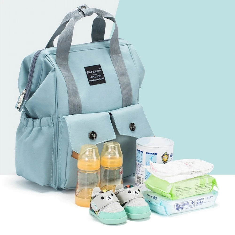 The Ellie & Luke Multifunctional Diaper Bag (Blue) by Ellie And Luke, with gray handles and insulated bottle holders, is open against a soft teal and white background. Visible inside are baby essentials like two yellow bottles, a can of formula, wipes, diapers, and panda-themed shoes.