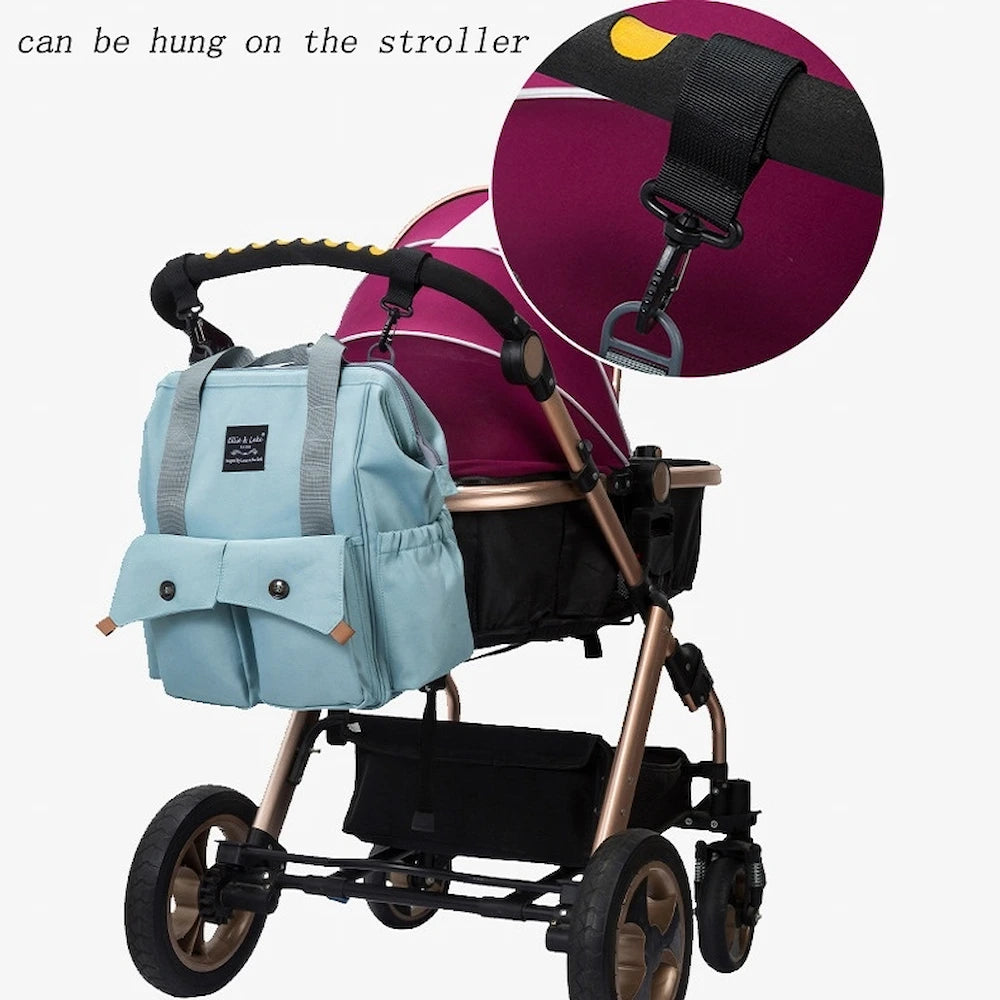 A stroller with a blue Ellie & Luke Multifunctional Diaper Bag hangs on its handle. A close-up shows the strap and hook system for securing the bag, which has insulated bottle holders. The stroller features a maroon canopy and black frame, with text noting it can be hung on the stroller.