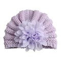 The Alaya Junior Baby Girl Lace Flower Design Knitted Turban Cap (0m-3Yrs) is a versatile accessory for any little one's wardrobe, featuring a lavender color and a large, decorative flower attached to the front.