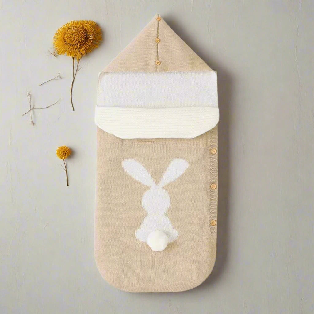 Beige baby swaddle with white bunny design on a white background