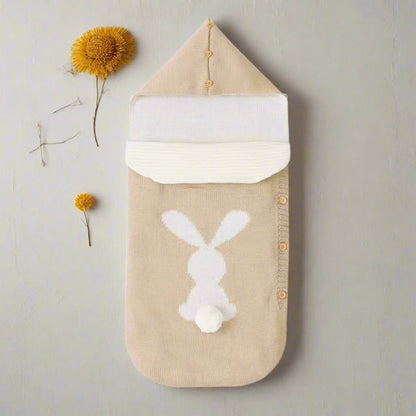 Beige baby swaddle with white bunny design on a white background