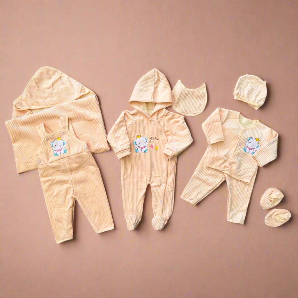 Collection of baby clothing items including rompers, a hat, and booties on a beige background