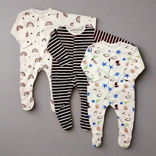 On a grey background are three adorable rompers from Carter's Baby Boy/Girl Pack of 3 Brown Lining Rompers. One romper showcases a delightful rainbow pattern, another features classic black and white stripes, and the third is adorned with an enchanting mix of clouds, stars, and animal prints—all made from super soft fabric ideal for little ones.