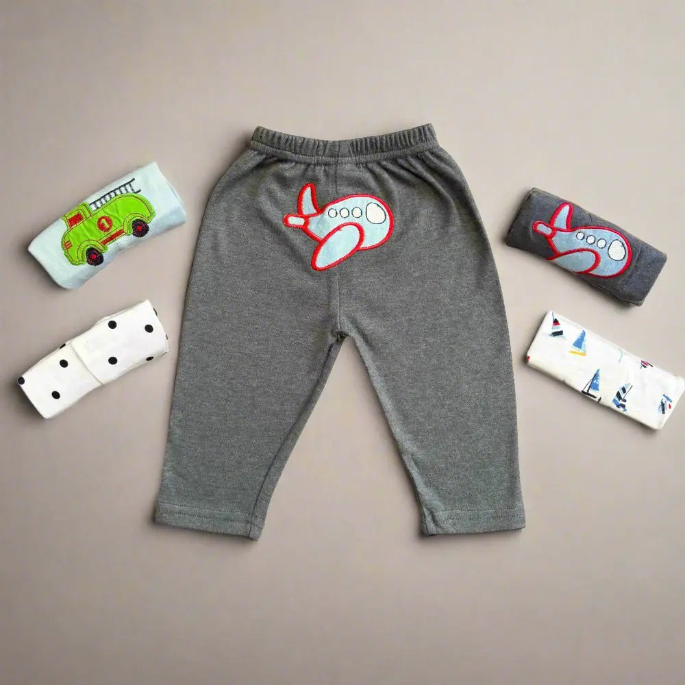 These unisex baby trousers from Alaya Junior are soft and comfortable, displaying a red airplane embroidery in the center. The pack includes four rolled shirts with charming vehicle themes, featuring green trucks and airplanes against diverse patterns such as polka dots on a neutral background.