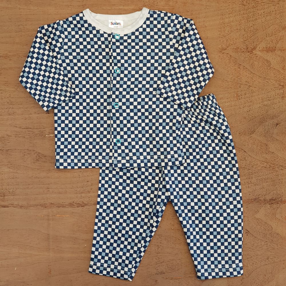 A children's outfit from Alaya Junior, featuring the Printed Dots Night Suit - JUNIORS, displayed on a wooden surface. Ideal for newborn baby attire in Pakistan, this set includes a matching long-sleeve shirt with front buttons and pants with an elastic waistband, both adorned with a charming blue and white checkerboard pattern.