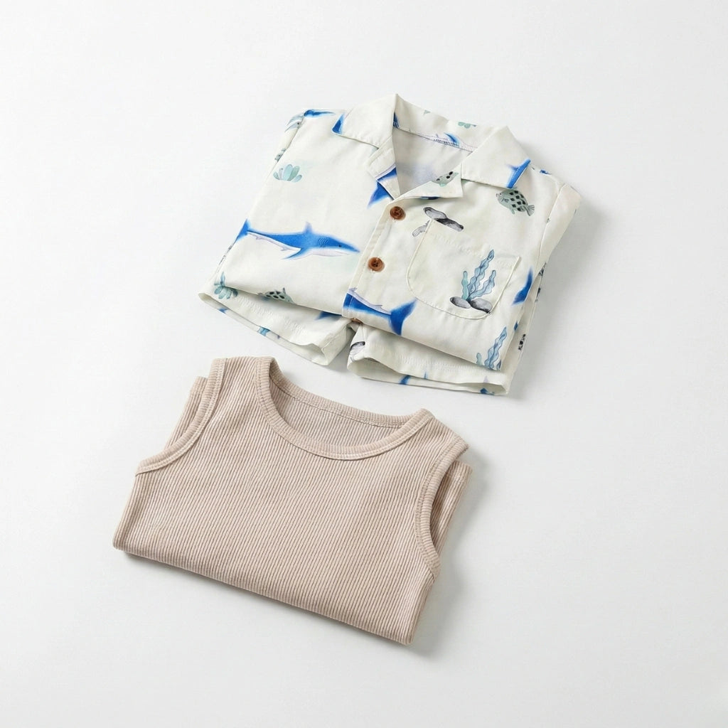 Folded children's shirt with blue whale pattern and beige ribbed tank top on a light gray background