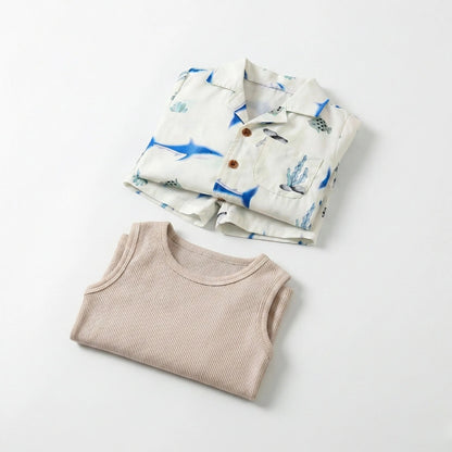 Folded children's shirt with blue whale pattern and beige ribbed tank top on a light gray background