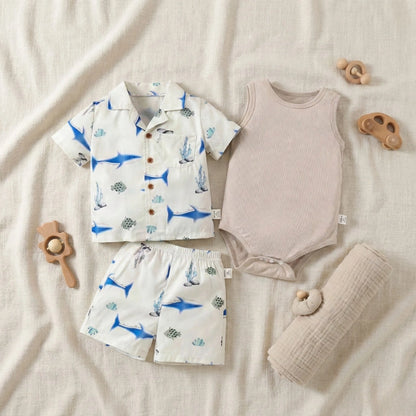 Children's clothing set with shirt, shorts, and romper on a soft surface with toys.