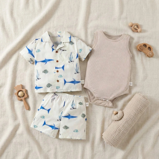 Children's clothing set with shirt, shorts, and romper on a soft surface with toys.