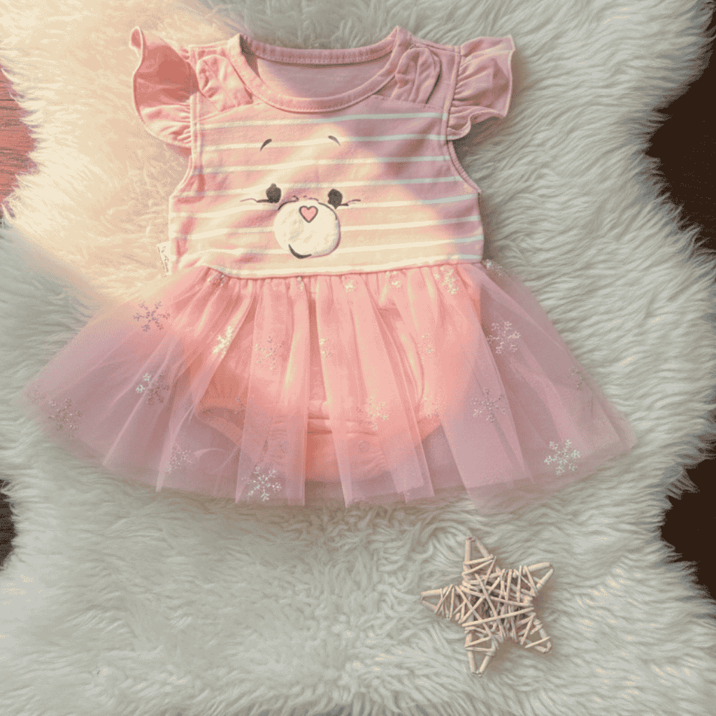 Pink dress with bear design on a fluffy white surface