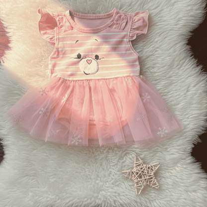Pink dress with bear design on a fluffy white surface