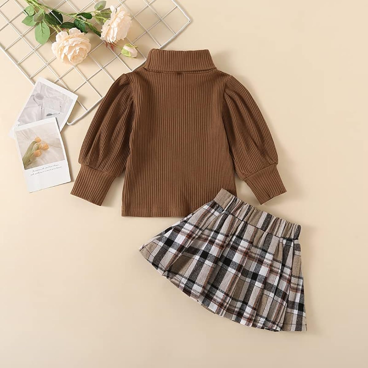 Brown ribbed sweater with puff sleeves and plaid skirt on a beige background