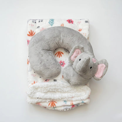 Gray elephant-shaped neck pillow on a floral-patterned blanket