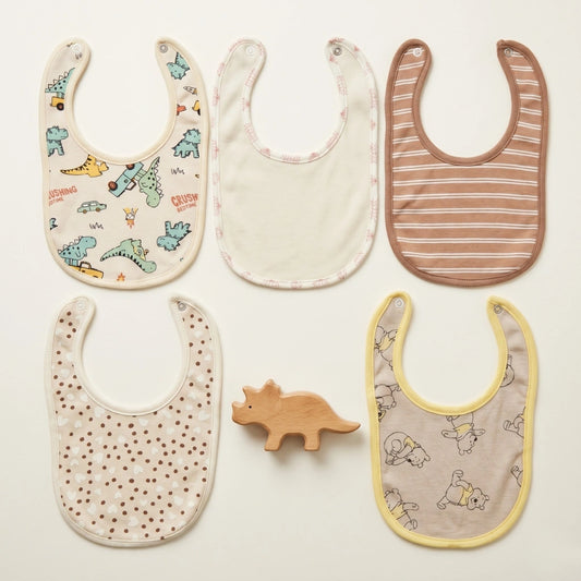 Five baby bibs with different patterns on a light background