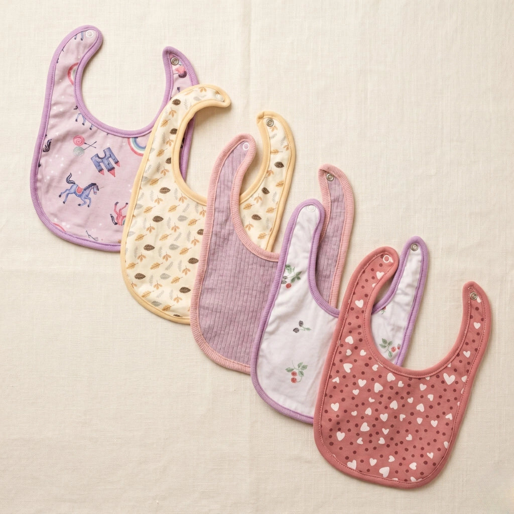 Set of five baby bibs with various patterns on a beige background