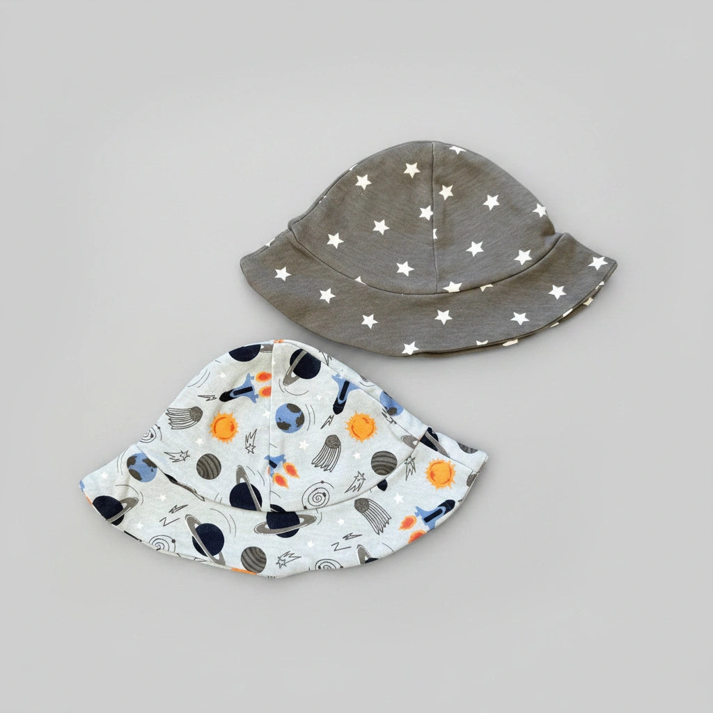 Gray bucket hat with white star pattern and colorful space-themed bib on a gray background