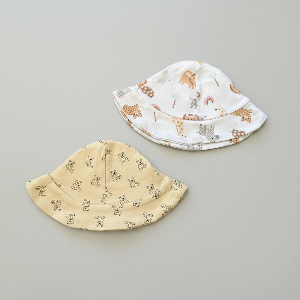 Two baby hats, one yellow with bear pattern and one white with animal pattern, on a gray background.