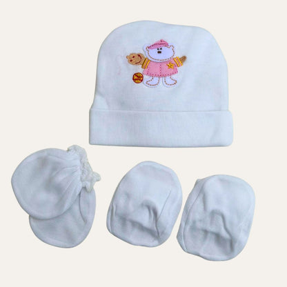 The Adorable White Newborn Cap, Mittens, and Booties Set - Little Theme Unisex Delight by Alaya Junior is perfect for newborns. The set features a white baby hat with an embroidered image of a small bear wearing a pink outfit, holding a teddy bear, and a star ornament. Accompanied by three pairs of white mittens, this set is ideal for infant clothing in Pakistan.