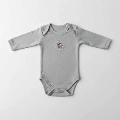 A light gray long-sleeve baby bodysuit with a small embroidered tiger logo on the chest, laid flat on a white shaggy faux fur rug.