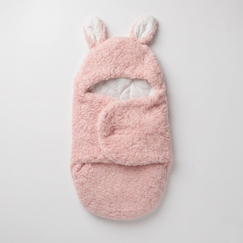 A pink plush baby bootie with bunny ears on the cuff, shown flat against a light gray background.