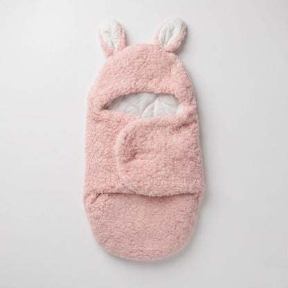 A pink plush baby bootie with bunny ears on the cuff, shown flat against a light gray background.