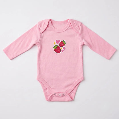 A light pink long-sleeve baby bodysuit with a graphic of two strawberries and small hearts on the chest, laid flat on a light gray background.