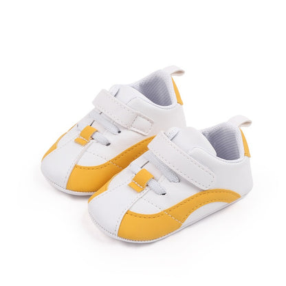 A stylish pair of Alaya Junior's Luxury Baby Shoes for Newborn Girls and Boys - Soft Sole Anti-Slip PU Leather Sneakers, perfect for enhancing any newborn outfit. These white and yellow baby shoes feature a convenient Velcro strap closure, sporty design with white soles, yellow accents along the sides and toes, and a soft inner lining to ensure ultimate comfort. Ideal for adding flair to baby clothing in Pakistan.