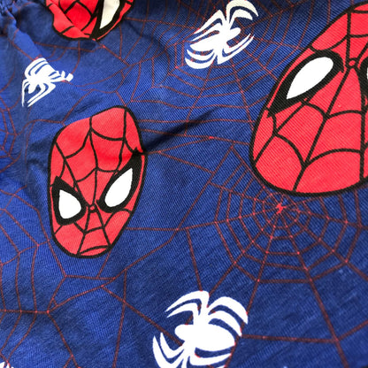 Close-up of a blue fabric featuring a pattern with Spider-Man's face in red, complemented by white spider icons and web designs. This vibrant and playful design is perfect for the Spider-Man Graphic Tee and Casual Short Set for Boys - Marvel 2-Pack by Alaya Junior, making it ideal for newborn baby clothing or themed merchandise commonly seen in infant clothing collections in Pakistan.