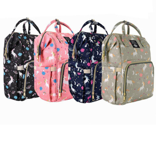 A row of four vibrant LEQUEEN Unicorn Mommy Diaper Bags by Alaya Junior, featuring playful patterns like unicorns and flowers, is displayed alongside charming infant clothing from Pakistan. The diaper bags are available in shades of black, pink, navy blue, and gray. Each bag comes equipped with a front zipper pocket, two top handles, and adjustable shoulder straps.